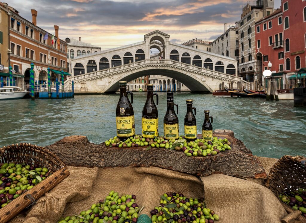 Passaggio sotto il Ponte di Rialto a Venezia e primo piano con Olio Extra Vergine Redoro Frantoi Veneti